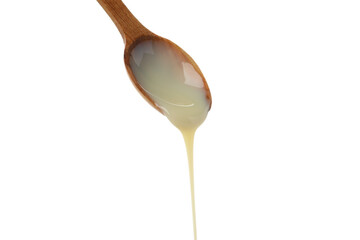 Spoon with dripping condensed milk isolated on white background