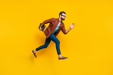 Full length body size photo of confident serious businessman running with computer doing project isolated on bright yellow color background