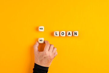 Wall Mural - The word loan on wooden blocks with a male hand choosing the no option. To deny a loan application or to reject loan