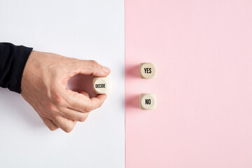 Wall Mural - male hand holding a wooden cube with the word decide pointing at the options of yes or no. dilemma o