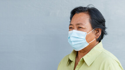 Close up portrait senior woman with black hair is looking at camera while wearing a protective mask during coronavirus. COVID-2019 