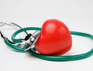 medical stethoscope and red rubber heart on white background