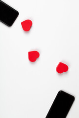 Red hearts and two mobile phones on white background. Internet dating, copy space