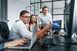 © standret - Sitting by the table. Team of stockbrokers works in modern office with many display screens