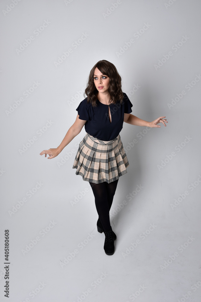 Full length portrait of pretty brunette woman wearing tartan skirt and ...