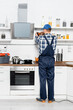 © LIGHTFIELD STUDIOS - back view of handyman with drill repairing shelves in kitchen