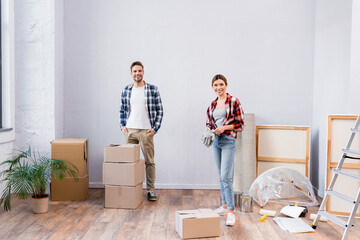 Canvas Print - full length of happy young couple looking at camera while standing in room during repair