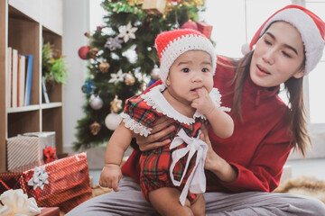 Wall Mural - merry christmas and happy Holidays. mother held her daughter near the christmas tree and decorate the christmas tree indoors. the morning before Xmas. Portrait loving family close up.