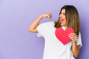 Young indian woman holding a valentines day heart isolated raising fist after a victory, winner concept.