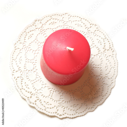 Single thick pink aromatic candle on white openwork paper napkin on white background top closeup view isolated 