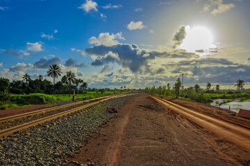 Sunset view of a typical red soils unpaved rough countryside road in Guinea, West Africa.