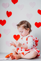 Little toddler girl in skirt with hearts on background with hearts celebrating Saint Valentine's day. Holiday decoration 