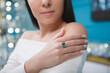 Cropped close up of a woman wearing expensive ring with emerald