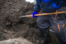 Details Of A Gravedigger Covering A Tomb With Dirt With A Shovel During A Burial Ceremony On A Cold And Snowy Winter Day.
