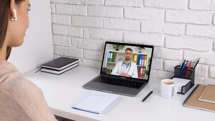 Woman patient client at home sitting on chair at table listen distance professional medical worker. Man doctor in laptop screen talk speak consults remote online conference video call computer webcam