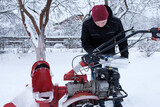 Fototapeta  - a man pours gasoline from a canister into a snow blower tank