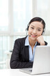 © eastfenceimage - Young woman using laptop and wearing headset