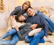 © soleg - portrait of a family sitting on a sofa at home, four people having fun together