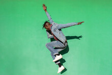 Young African Man Jumping Up Isolated On Green Colored Background.