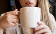 © Jose Carlos Ichiro/Westend61 - Woman blowing coffee while holding coffee cup at cafe
