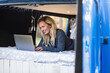 © William Perugini/Westend61 - Smiling woman using laptop while lying on bed in van