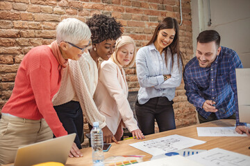 Wall Mural - Creative young business people working on business project in office. Cheerful business people laughing in office. Multi-ethnic group of business persons talking in the office