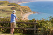 Person takes in the view out to sea from the top of Golden Cap in West Dorset, England, with background view of Bridport sandstone cliffs and Chesil beach
