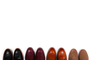 Poster - Bunch of different style men's shoes in a row. Close up shot chukka boots, single and double monk strap oxfords, brown, black and burgundy brogues. Top view, copy space, flat lay, white background