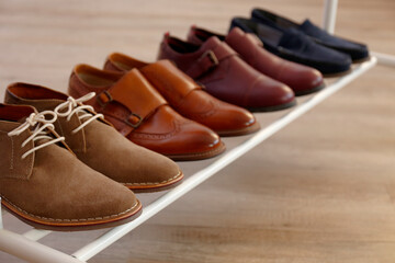 Poster - Bunch of different style men's shoes in a row. Close up shot chukka boots, single and double monk strap oxfords, brown, black and burgundy brogues. Top view, copy space, flat lay, wooden background