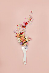 Brush paints with flowers, spring concept on pastel pink background. Minimal nature flat lay