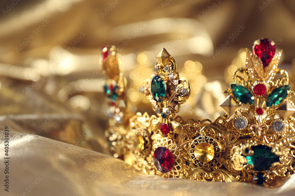Beautiful ancient crown on golden fabric, closeup. Fantasy item - obrazy, fototapety, plakaty 