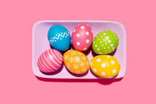 Handmade Painted Easter Eggs In Purple Tray On Pink Background
