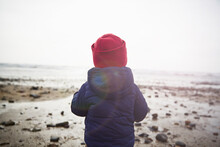 Rear View Of Male Toddler On Beach Gazing At Sea