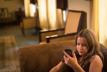 Girl Sitting On Sofa Texting On Smartphone