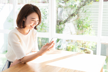 Wall Mural - 部屋でスマホを見る女性