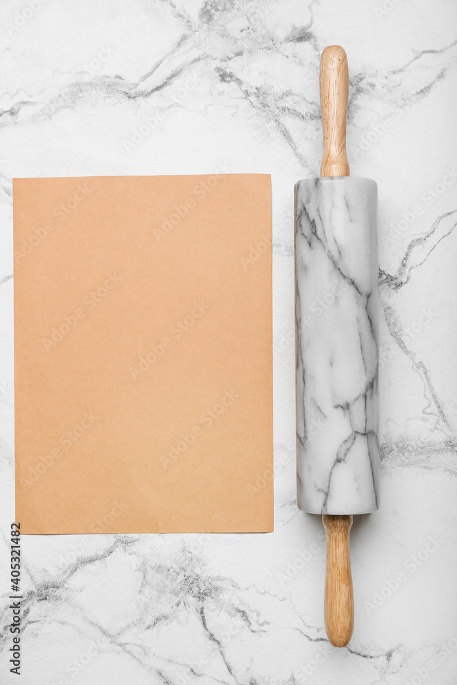 Rolling pin and blank paper sheet on light background