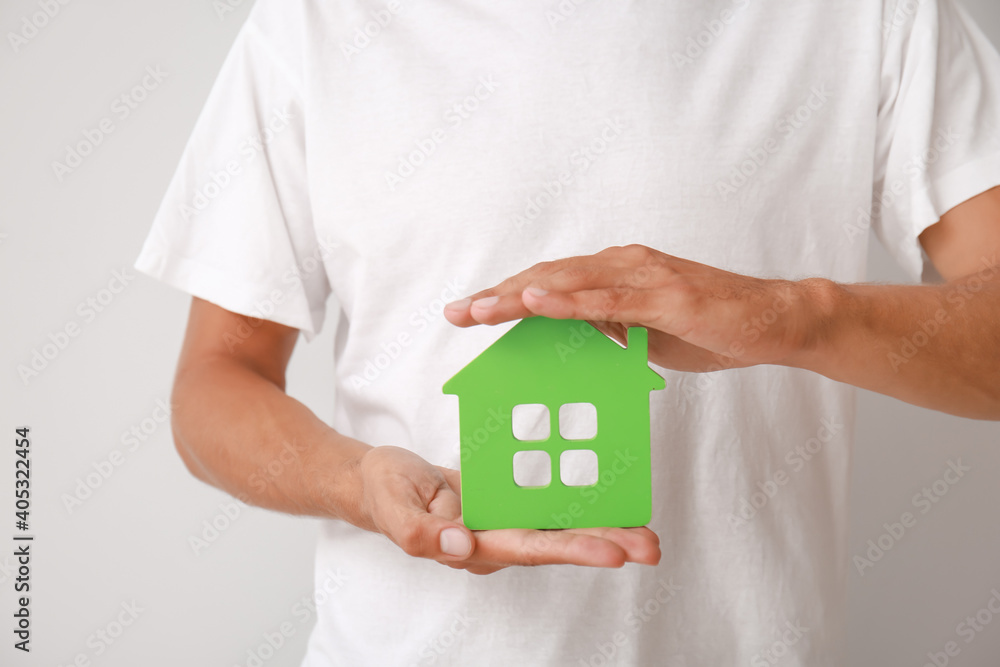 Male hands with figure of house on light background