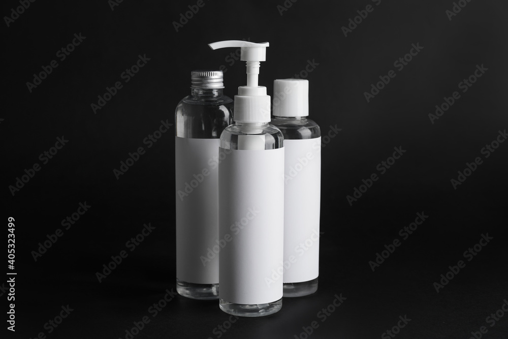 Different bottles of cosmetic products on black background