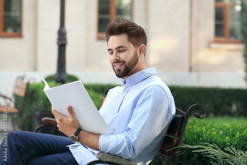 Young man with blank magazine in park