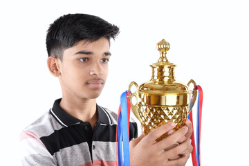 Indian school boy holding a golden trophy cup	
