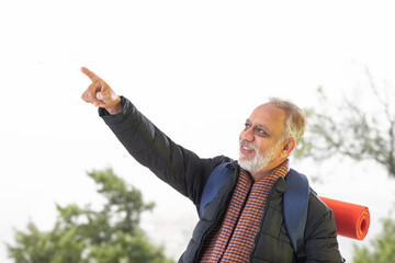 A SENIOR ADULT MAN POINTING FAR AWAY WHILE MOVING	