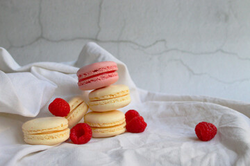 Photo of pink and white macaroon with raspberries on crumpled linen cloth