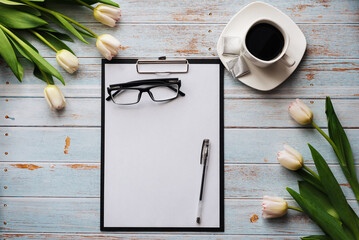 Wall Mural - bouquet of white tulips with an empty paper tablet and a Cup of coffee on a wooden table