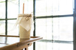 © Parviza - Paper coffee cup with straw made from sugar product on near window of cafe.