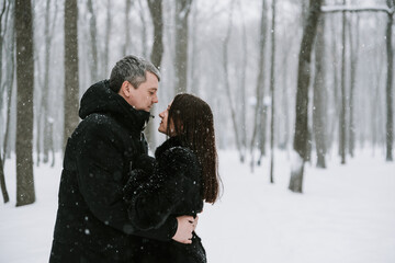 A man and a woman on the background of a snow-covered forest in a snowfall