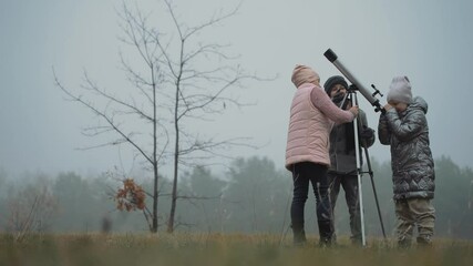 little boy and girls looking through a telescope in the nature. kids interested in astronomy and sci