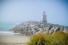 Lighthouse On Beach By Sea Against Sky