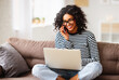 © JenkoAtaman - Cheerful ethnic woman with laptop speaking on smartphone