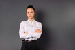 © Viorel - Serious business woman has her hands intertwined and looks at the camera on a gray background. Empty side space.