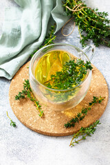 Therapeutic herbal tea. Hot cup of thyme tea on a light stone countertop. Copy space.